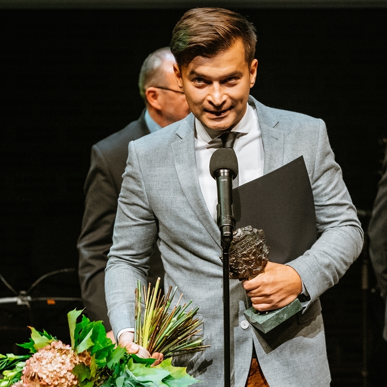 Jakub Małecki stoi przy mikrofonie