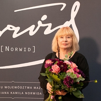 Anna Beata Wątróbska-Wdowiarska stoi z kwiatami w ręku.